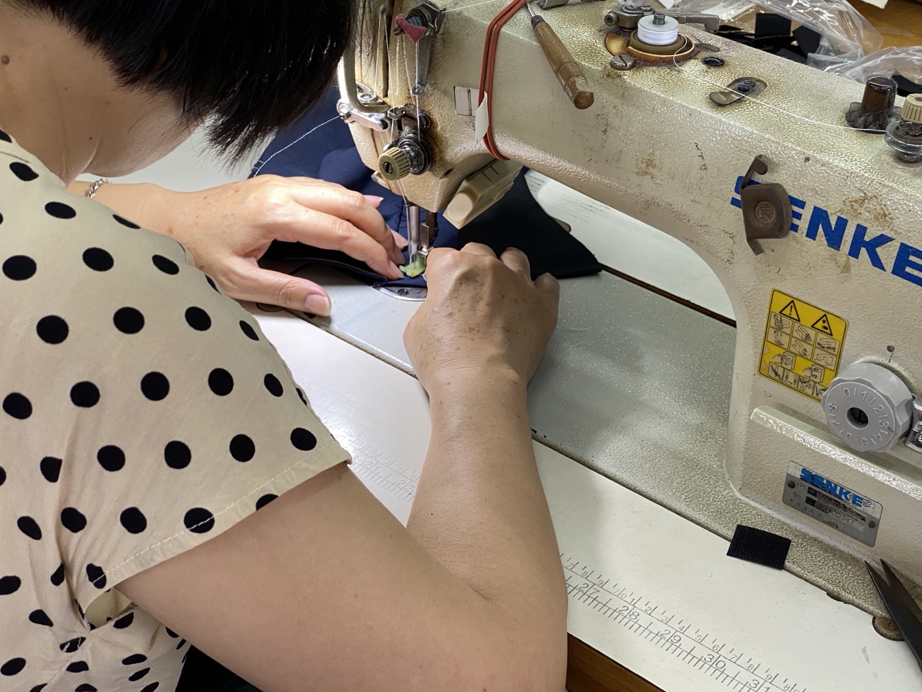 Close-up of an operator sewing unbranded navy fabric