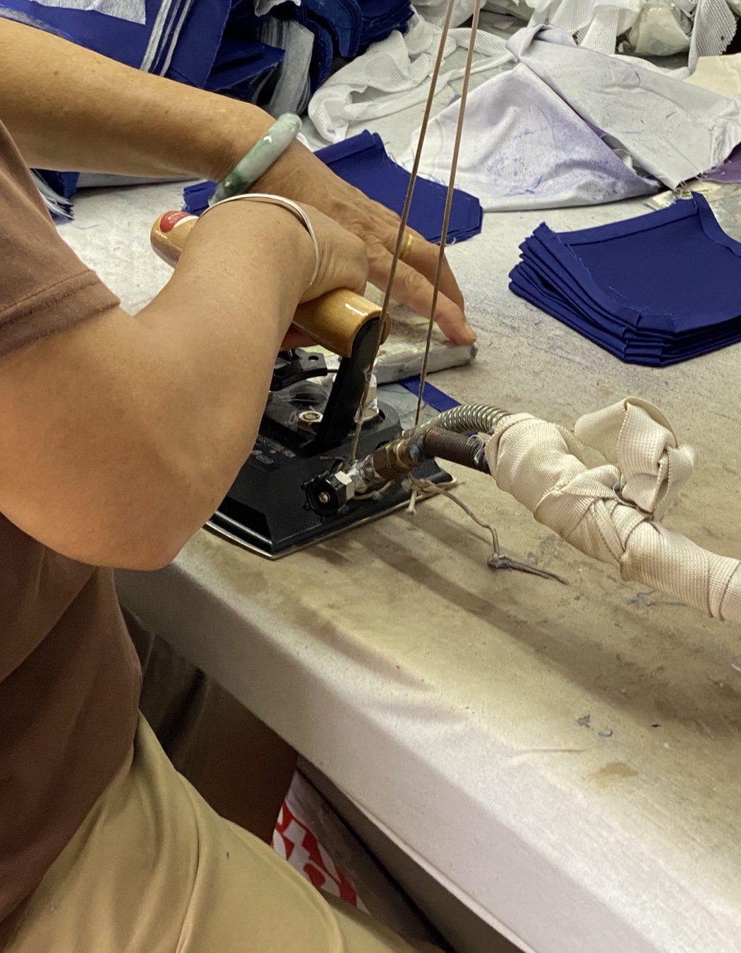 Operator preparing unbranded navy trim pieces with a hot-cut tool