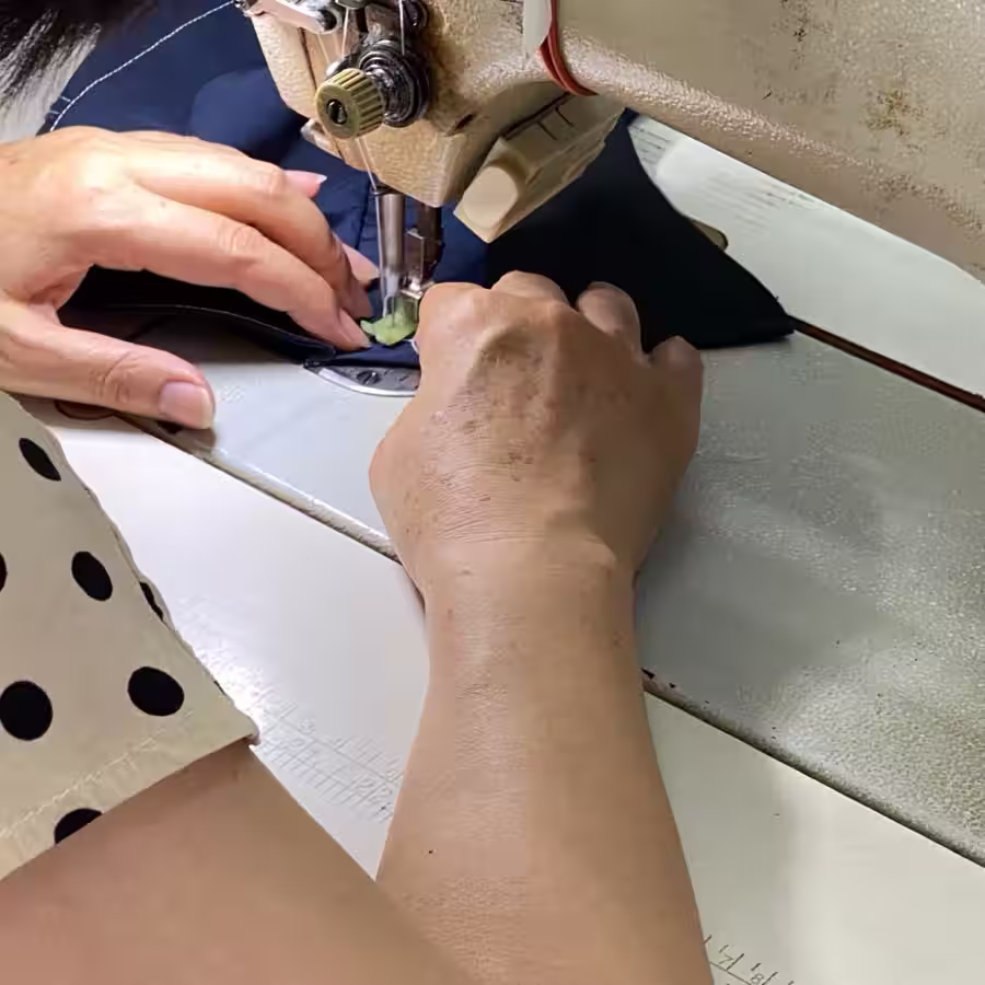 Close-up of an operator sewing plain navy garment material