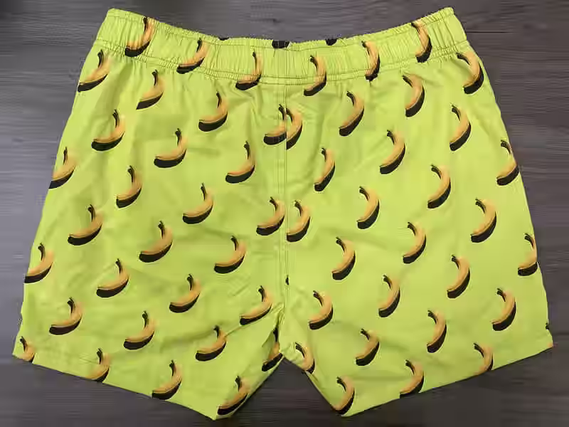 Front view of lime elastic-waist swim shorts with banana print