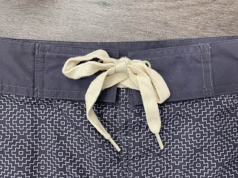 Contrast waistband and drawcord detail on charcoal micro-geometric board shorts