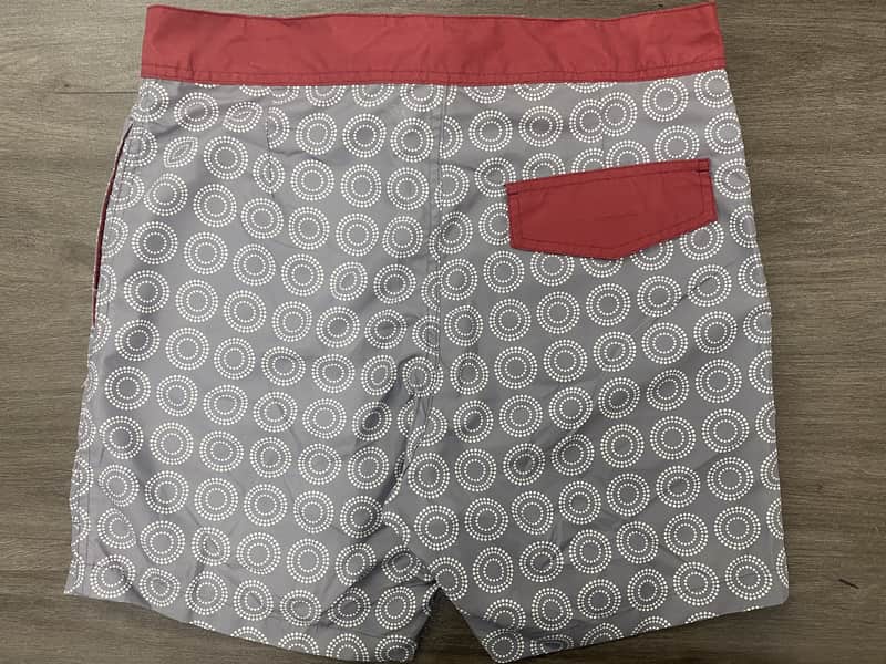 Back view of gray circular geometric board shorts with contrast pocket