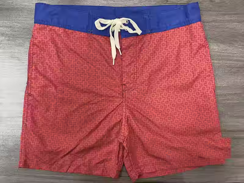 Front view of coral micro-geometric fixed-waist board shorts