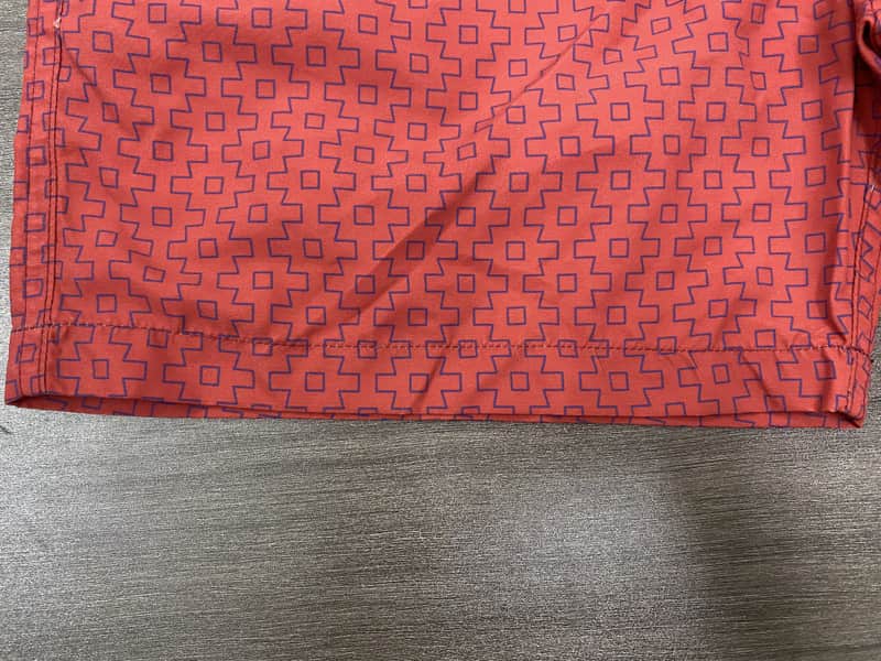 Hem and coral micro-geometric repeat detail on board shorts