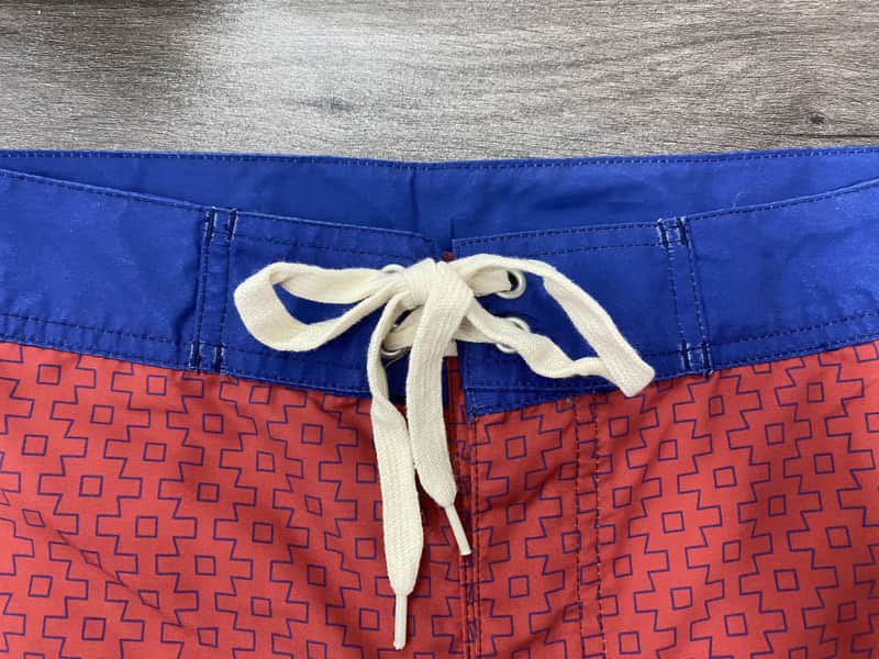 Royal-blue waistband and drawcord detail on coral micro-geometric board shorts