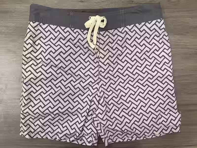 Front view of fixed-waist board shorts with black and white maze print