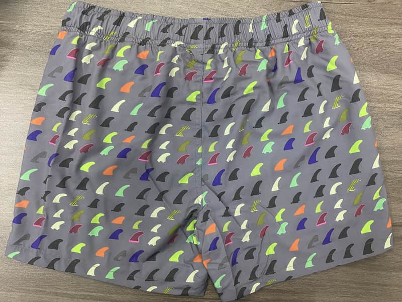 Back view of gray elastic-waist swim shorts with multicolor fin print
