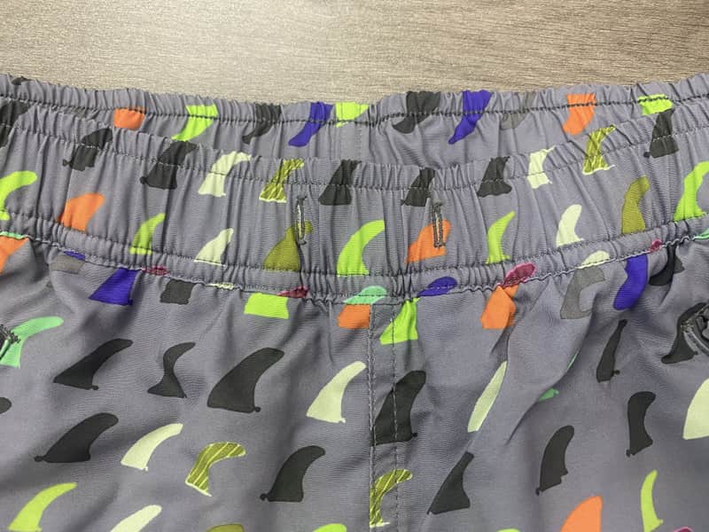 Elastic waistband detail on gray multicolor fin print swim shorts