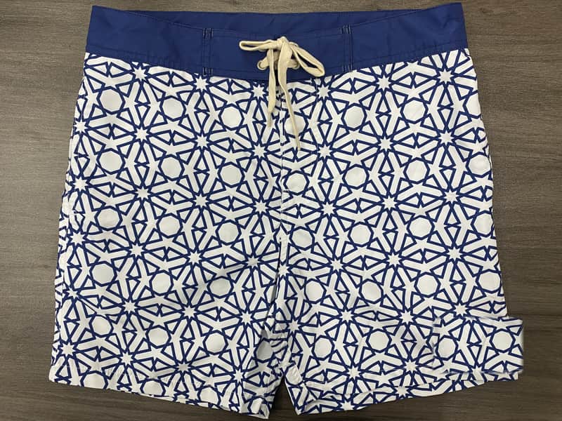 Front view of self-owned navy and white abstract geometric fixed-waist board shorts