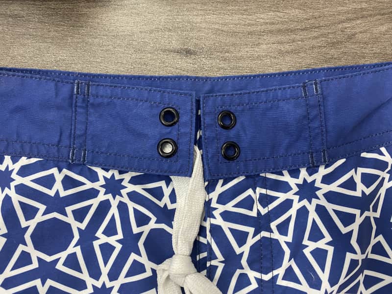 Solid waistband and lace-up detail on navy abstract board shorts