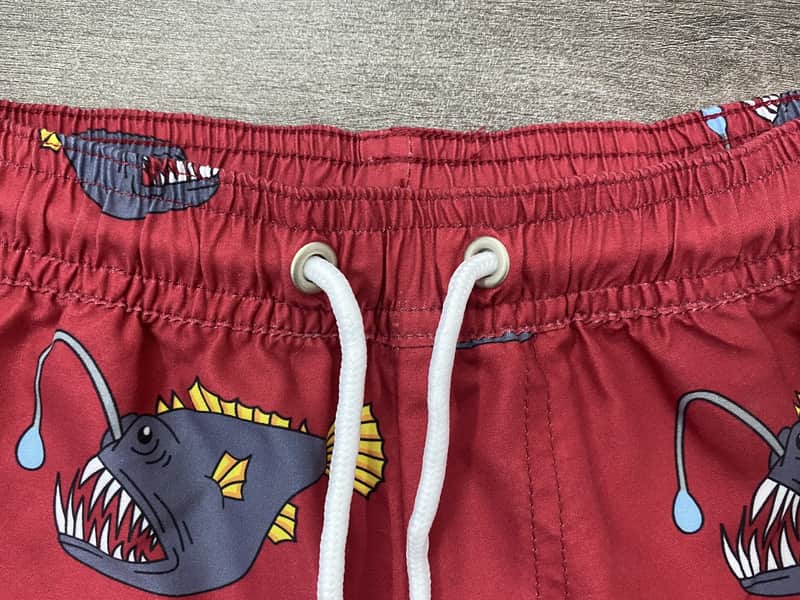 Elastic waistband and drawcord detail on red fish print swim shorts