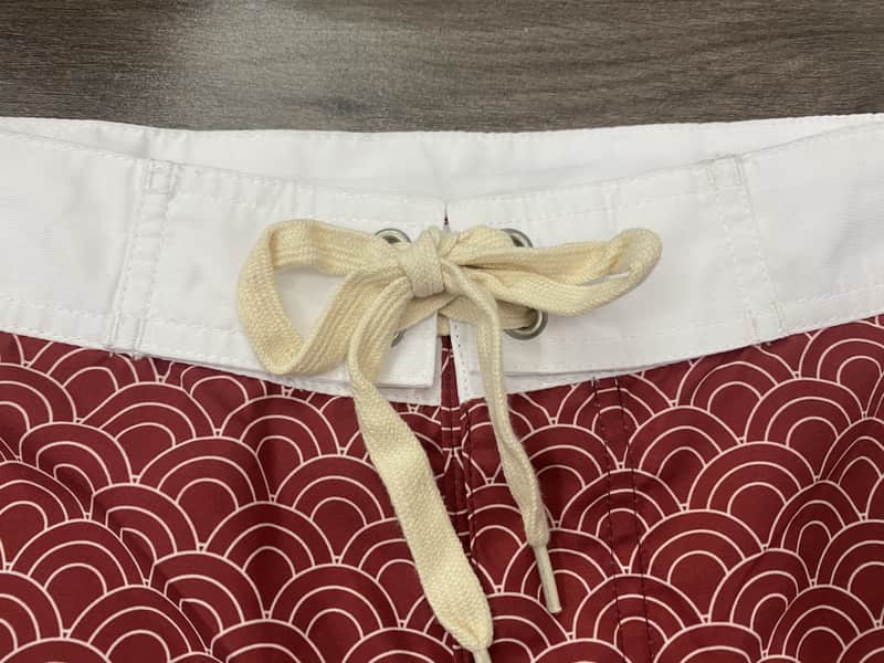 White waistband and drawcord detail on red wave print board shorts