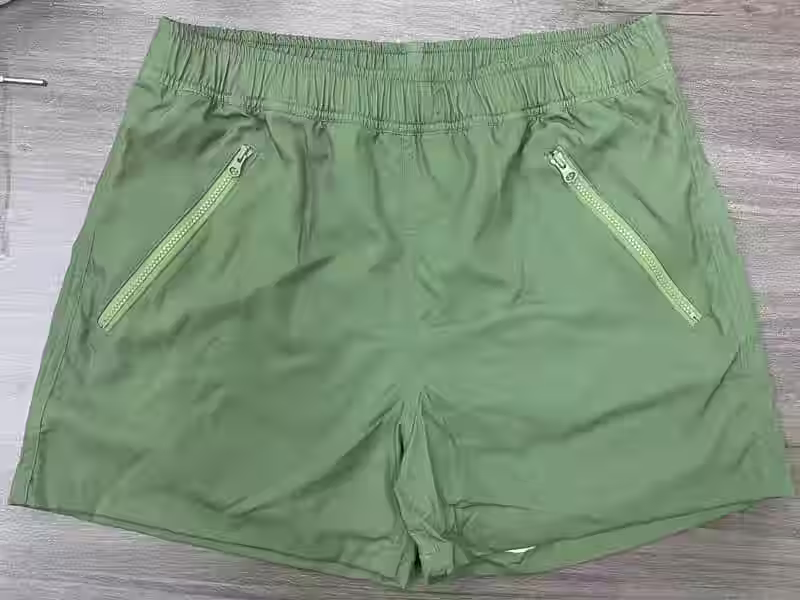Front view of sage solid elastic-waist swim shorts with zipper pockets