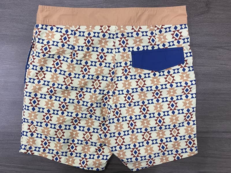 Back view of sand geometric swim shorts with blue contrast pocket
