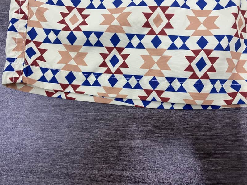 Hem and horizontal geometric band detail on sand swim shorts