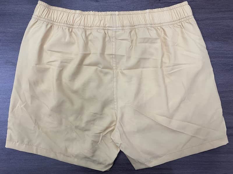 Back view of sand solid elastic-waist swim shorts