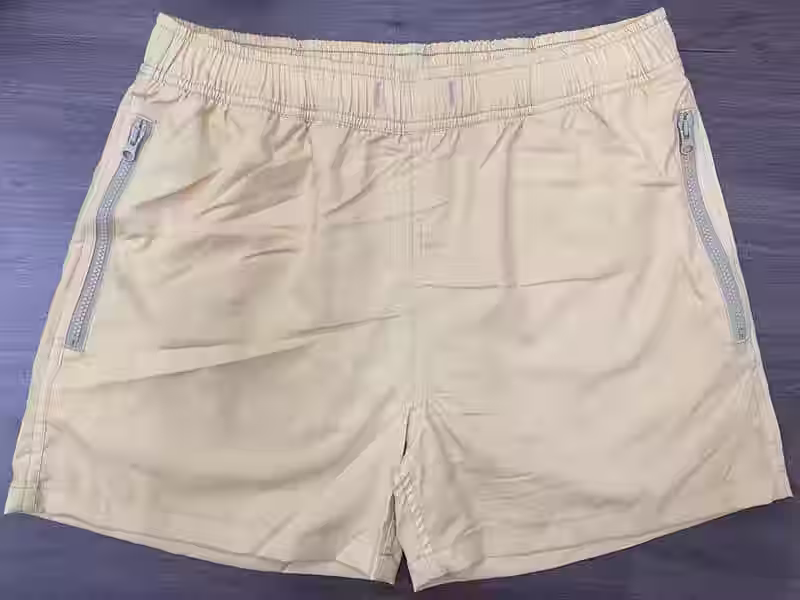 Front view of sand solid elastic-waist swim shorts with angled zipper pockets