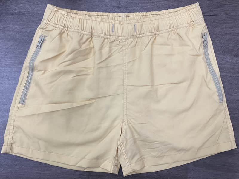 Front view of self-owned sand solid elastic-waist swim shorts with angled zipper pockets