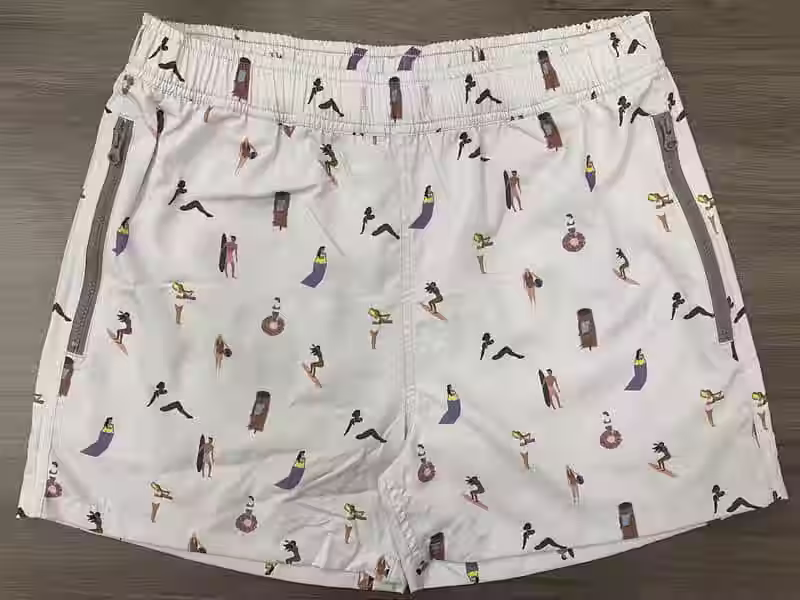 Front view of elastic-waist swim shorts with a small surfer-figure print