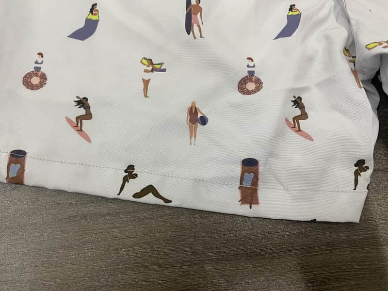 Close view of the hem and print scale on small surfer-figure print swim shorts
